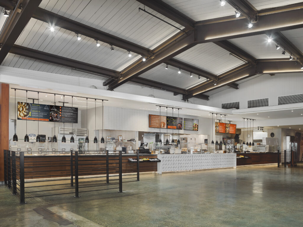 An interior view of a modern restaurant serving counter with menu boards mounted above.