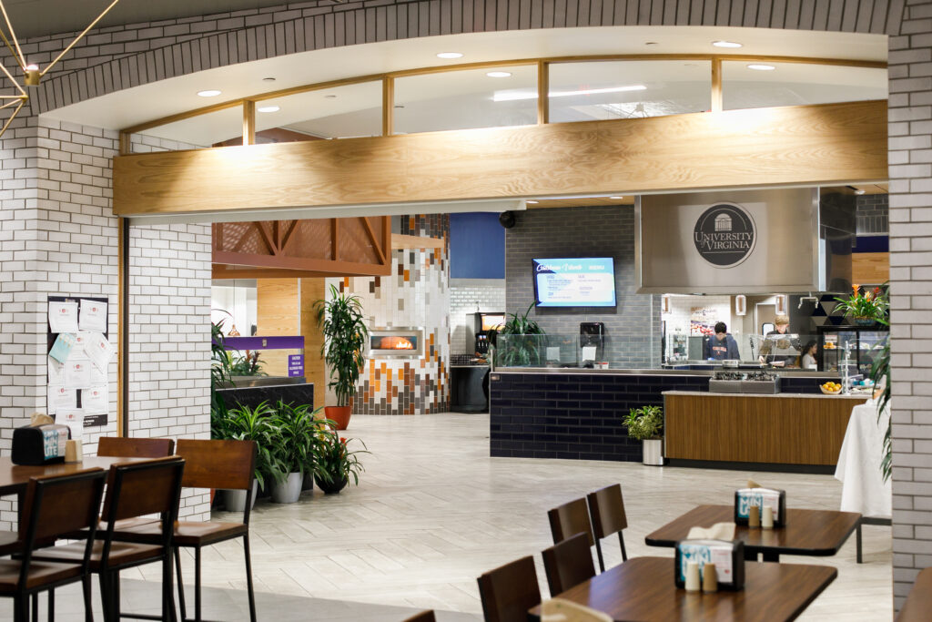Interior of a dining hall at the University of Virginia, featuring a serving counter, a brick oven, and dining tables.