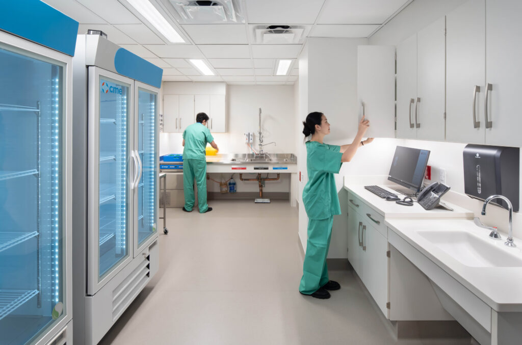 Two medical professionals in scrubs working in a clinical prep room.