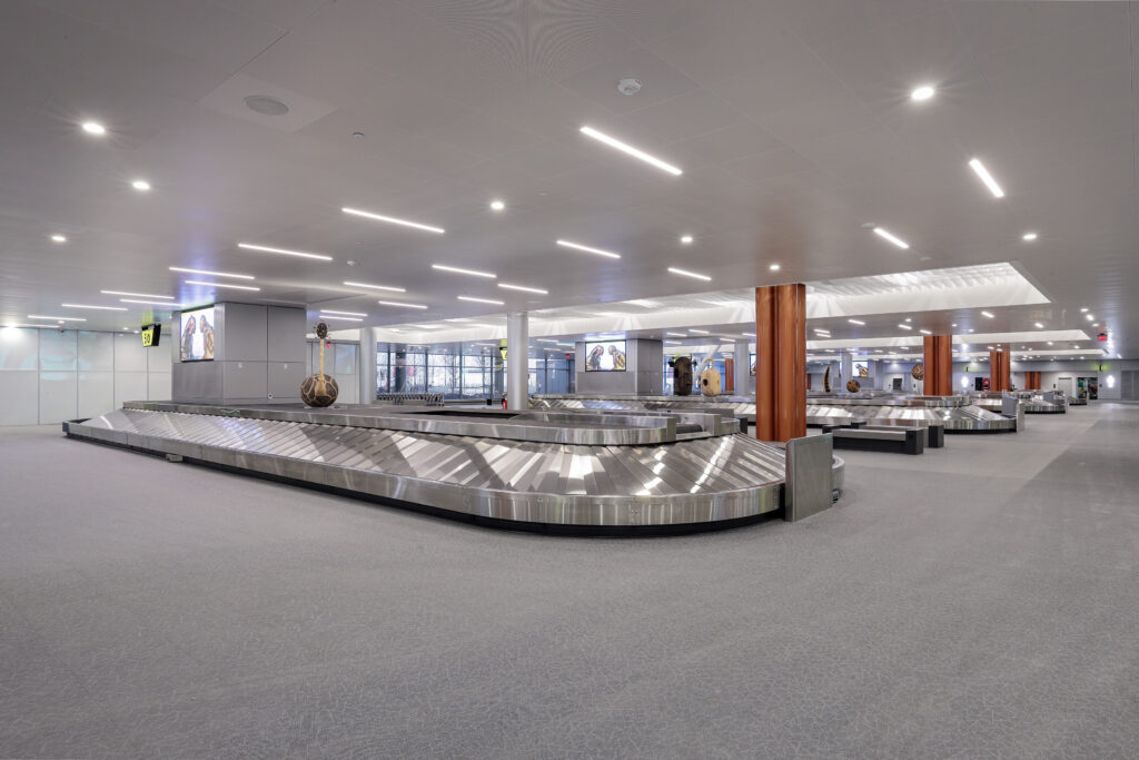 Empty airport baggage claim area with large stainless steel luggage carousels.