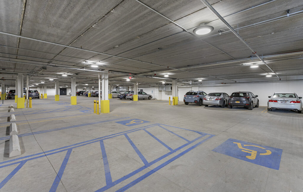 An indoor parking garage with marked accessible parking spaces and several parked vehicles.