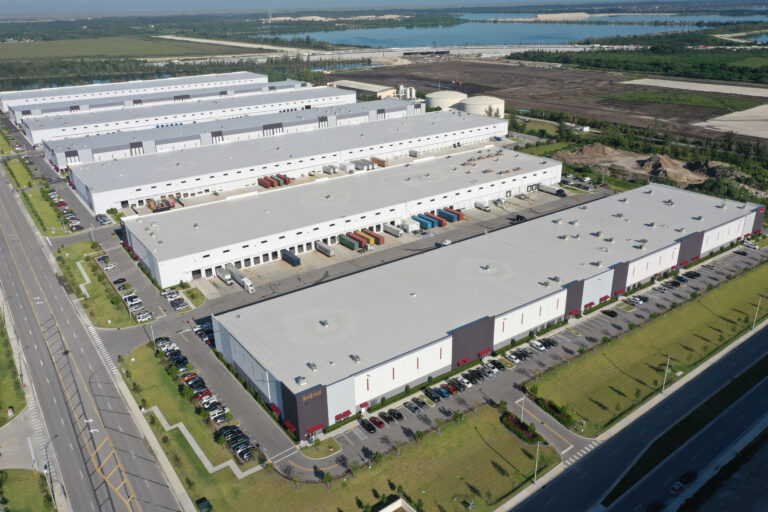Aerial view of a large warehouse complex with multiple loading docks, shipping containers, and parking lots.