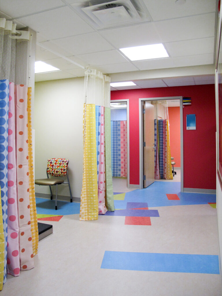 A pediatric clinic hallway with colorful curtains, bright walls, and patterned floor tiles.