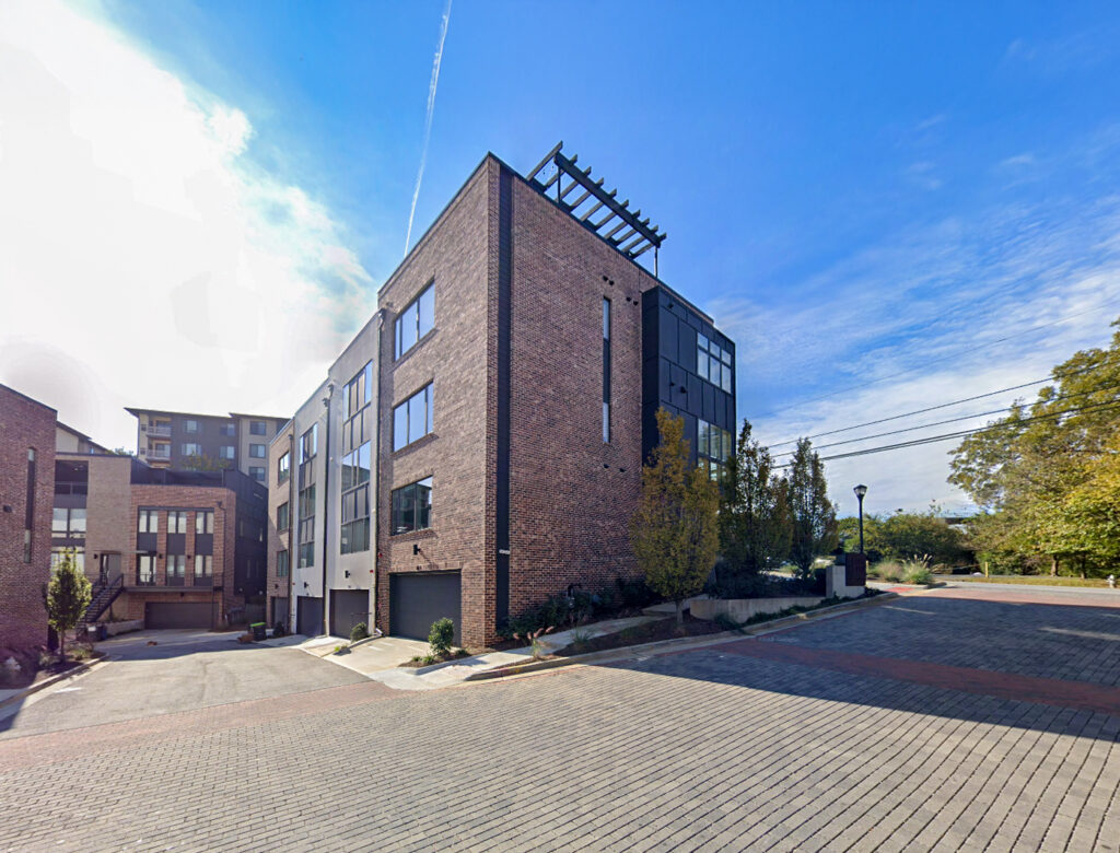 Modern apartment building with a brick and black facade at the corner of a paved street.