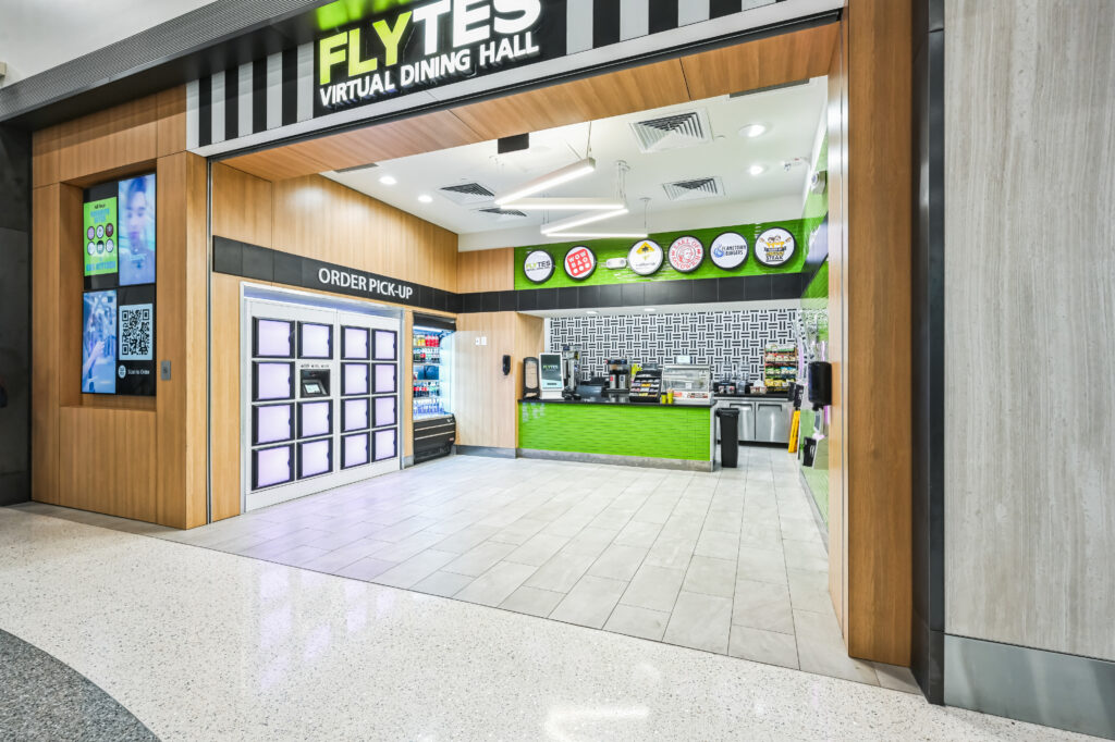 The entrance to Flytes Virtual Dining Hall, featuring a row of order pick-up lockers, a service counter with menu logos, and a digital ordering kiosk on the left.