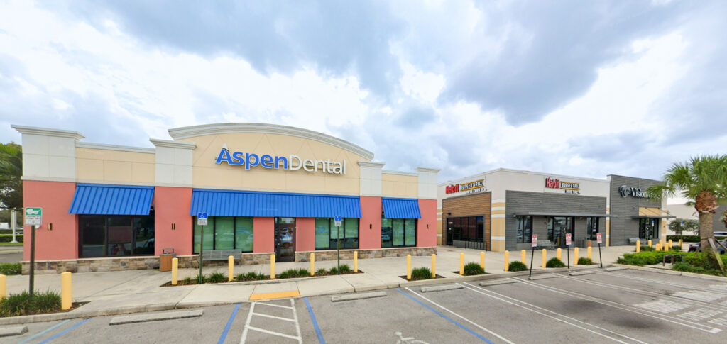 A strip mall featuring an Aspen Dental office, a Habit Burger Grill, and a Visionworks store.
