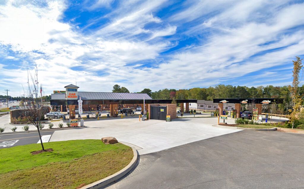 A gas station and car wash with multiple fueling pumps under a long canopy.