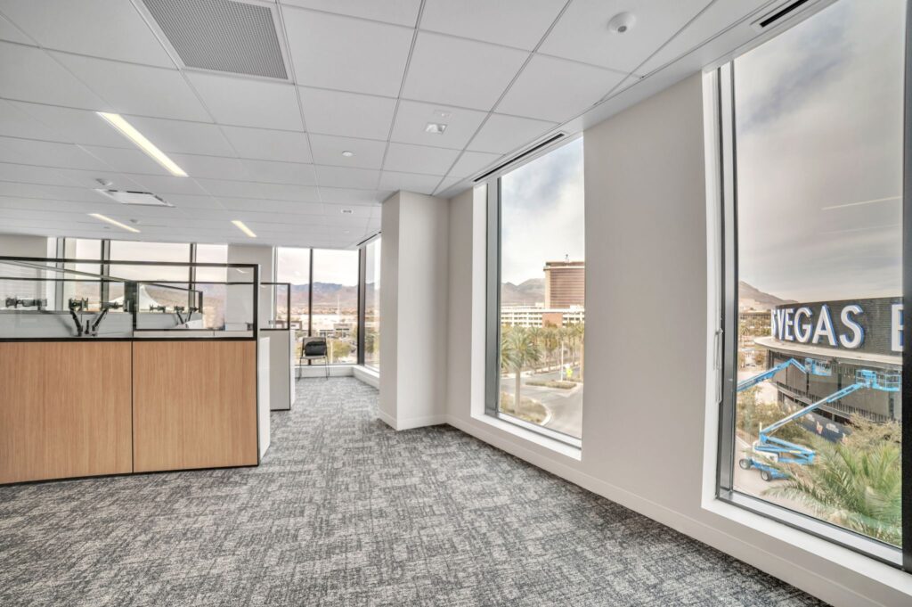 Empty office space with cubicle partitions and large windows overlooking the Las Vegas Strip.