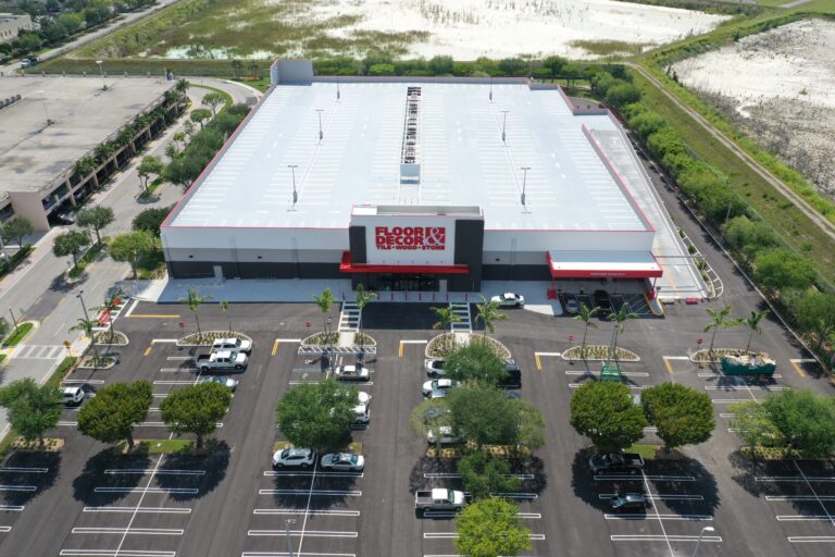 Aerial view of a Floor & Decor store with a large rooftop parking lot and a surface parking lot in front.