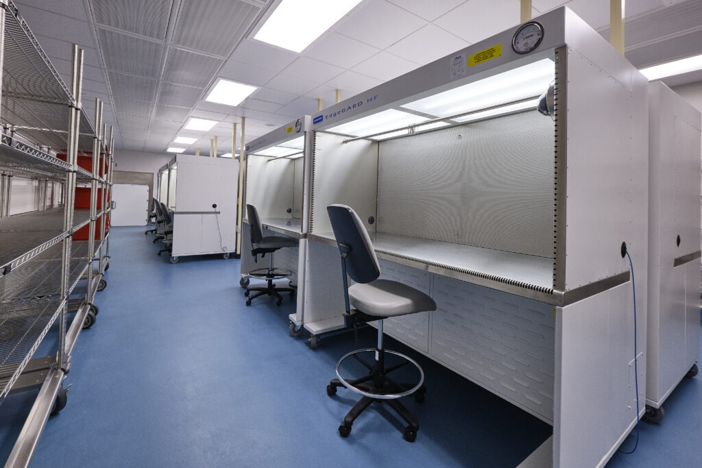 A row of cleanroom workstations with rolling chairs in a laboratory.