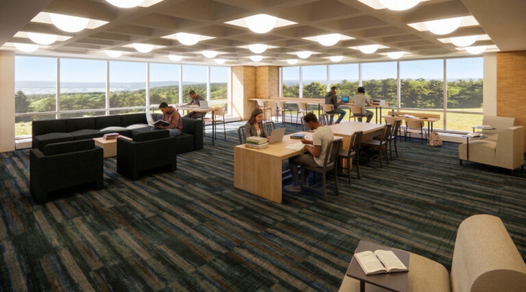 A bright, modern library study area with several students seated at tables and sofas, set against large windows overlooking a green landscape.