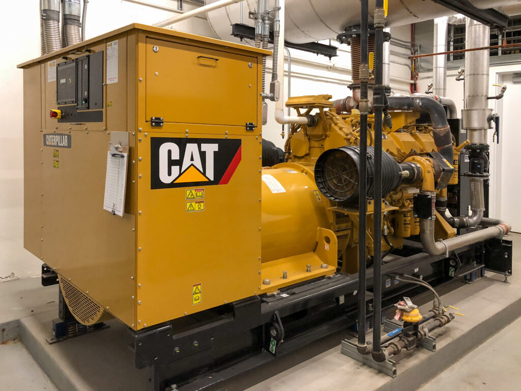 Large yellow industrial Caterpillar backup generator in a mechanical room.