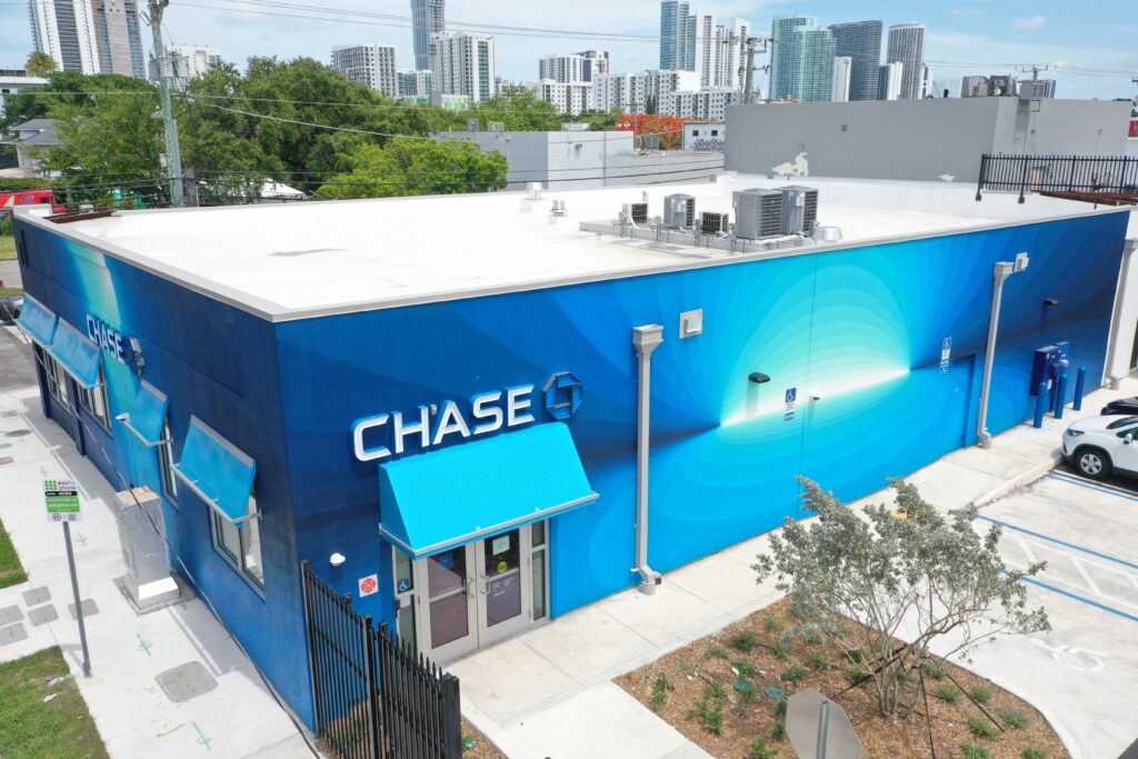 A Chase bank branch featuring a blue building exterior with a radiating blue mural, viewed from an elevated angle.