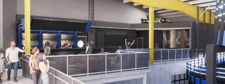 A multi-level sports bar or lounge with a bar counter, seating areas, a racing car display, and people socializing.