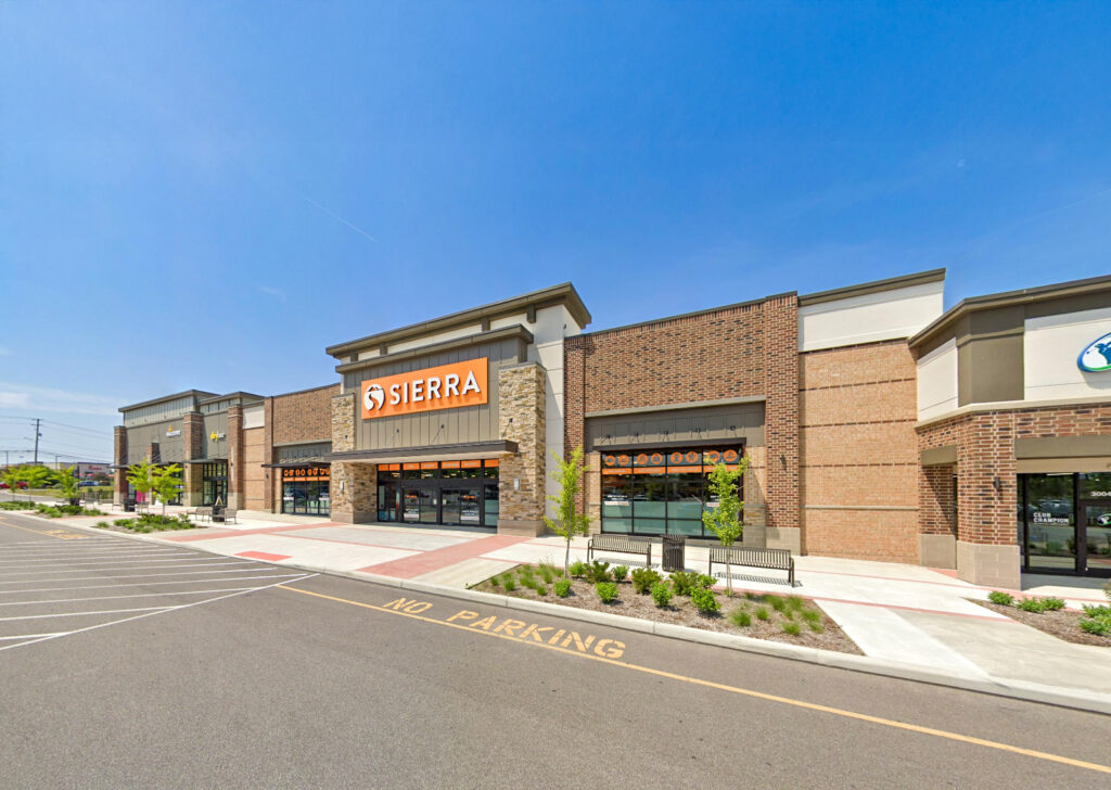 A Sierra store storefront in a suburban shopping plaza with “NO PARKING” painted on the asphalt.