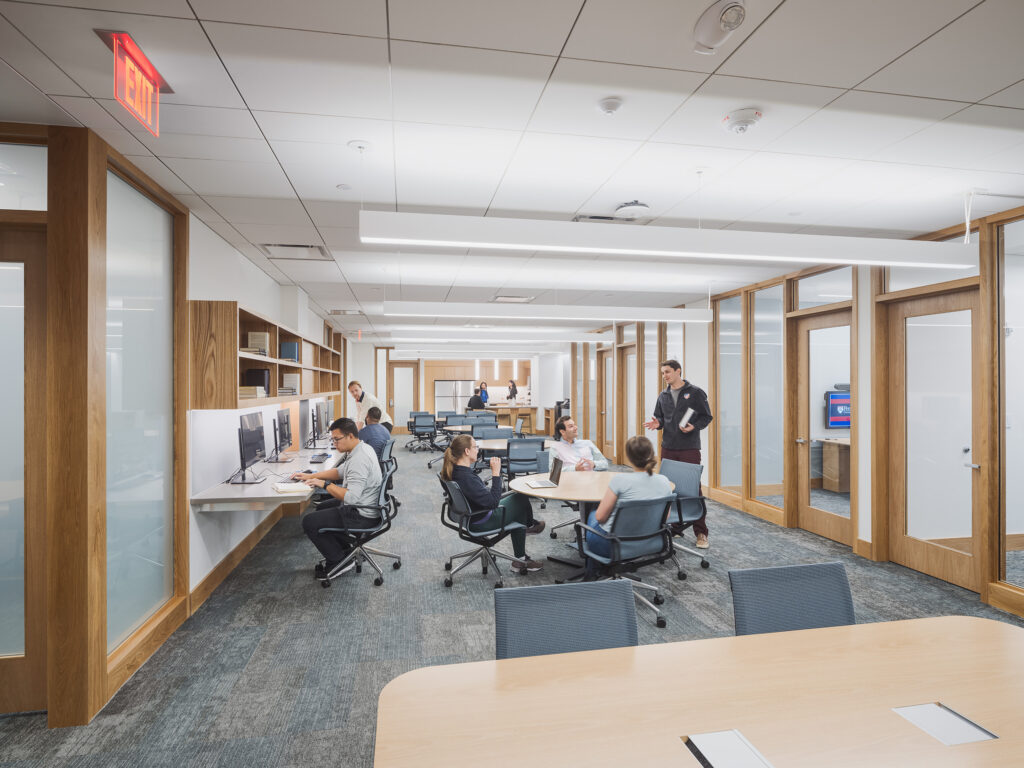 People working at desks and sitting at a round table in an open-plan office.