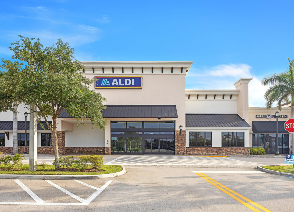 Aldi store exterior with a parking lot and a tree in the foreground.