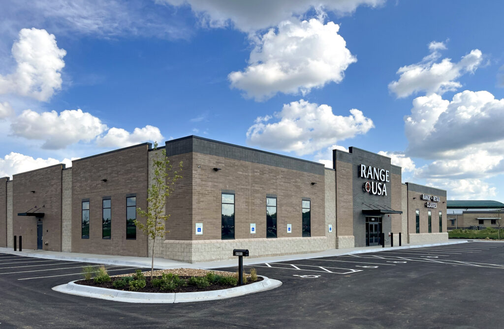 Exterior of a Range USA building with a brick facade and an adjacent parking lot under a blue sky.