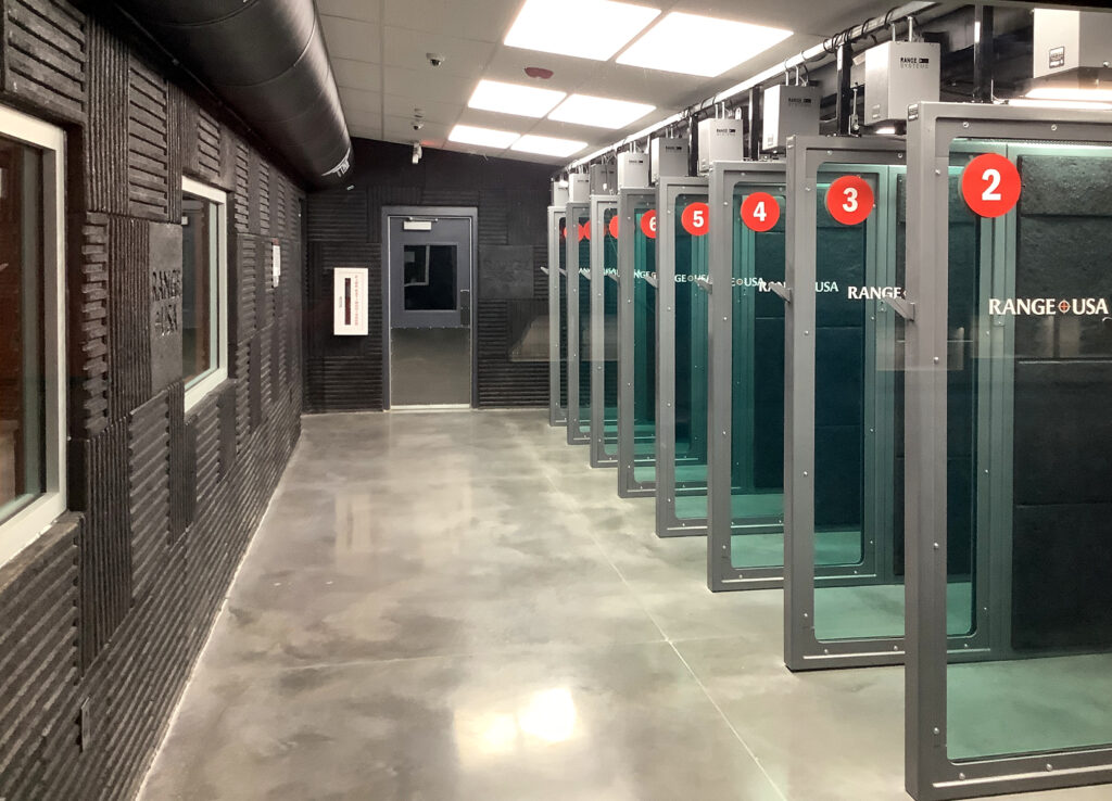 A row of indoor shooting range stalls numbered two through six.