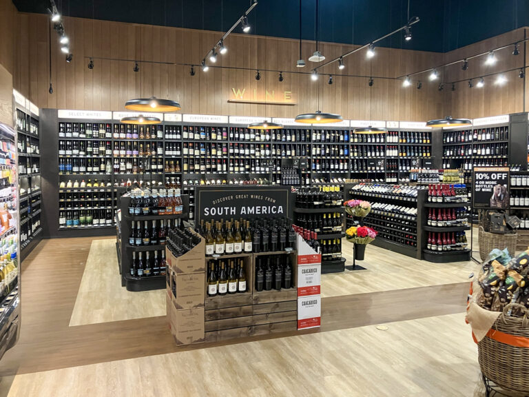 Wine store interior with shelves stocked with bottles and a featured display of South American wines in the center.