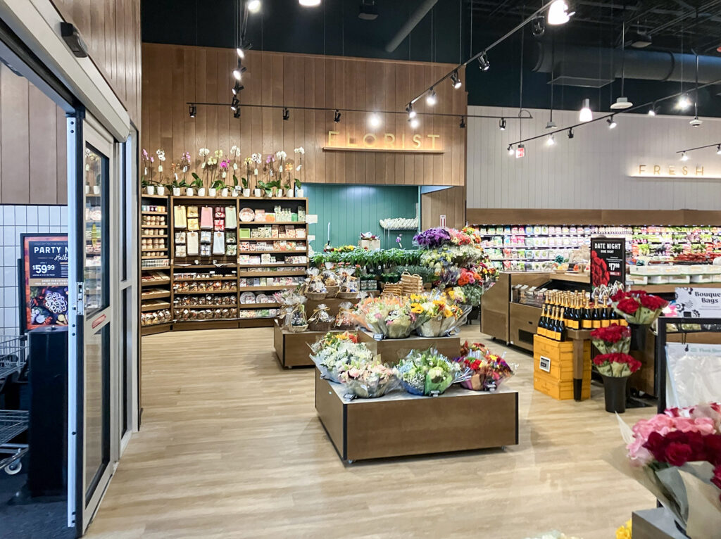 Interior of a grocery store florist department with displays of fresh bouquets and shelves of floral supplies.