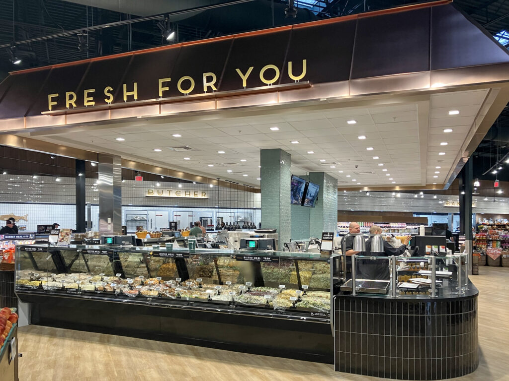 A grocery store “Fresh For You” deli counter featuring a glass-fronted display case filled with prepared meals.
