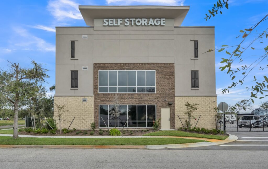 A multi-story self-storage facility with a light-colored facade, brick accents, and large windows.