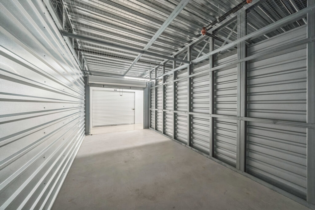 Empty self-storage unit with corrugated metal walls and a concrete floor.