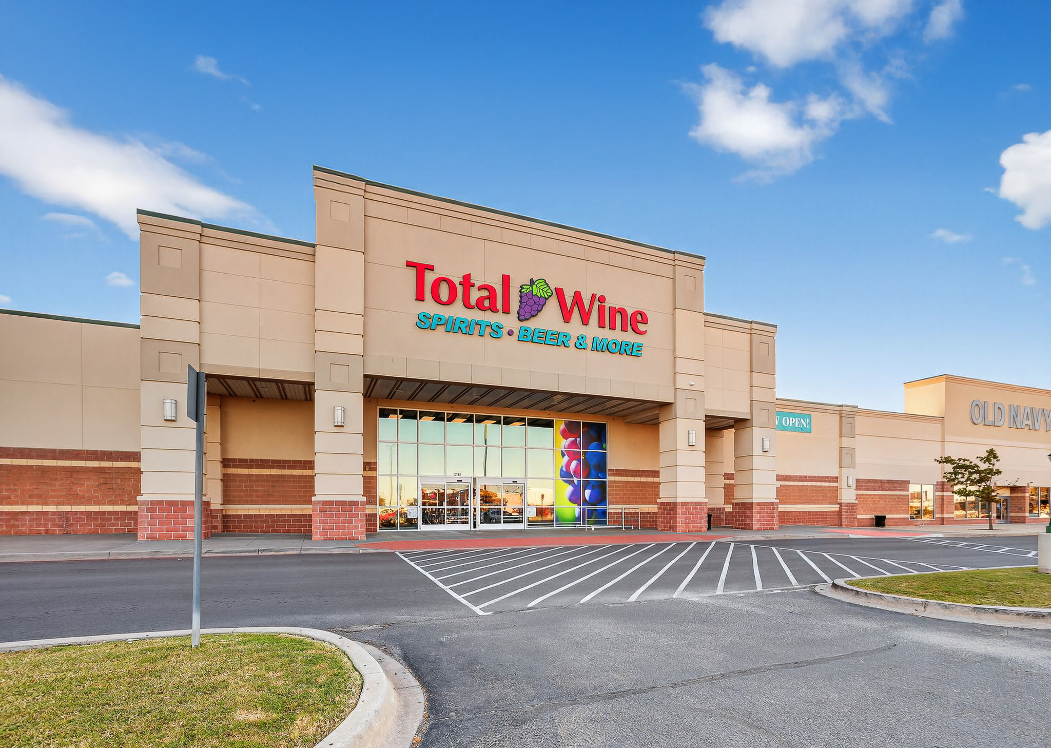 Exterior of a Total Wine & More store in a shopping center under a clear blue sky.