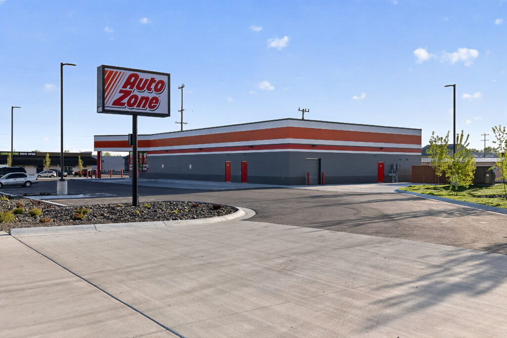 AutoZone store building and parking lot under a blue sky.