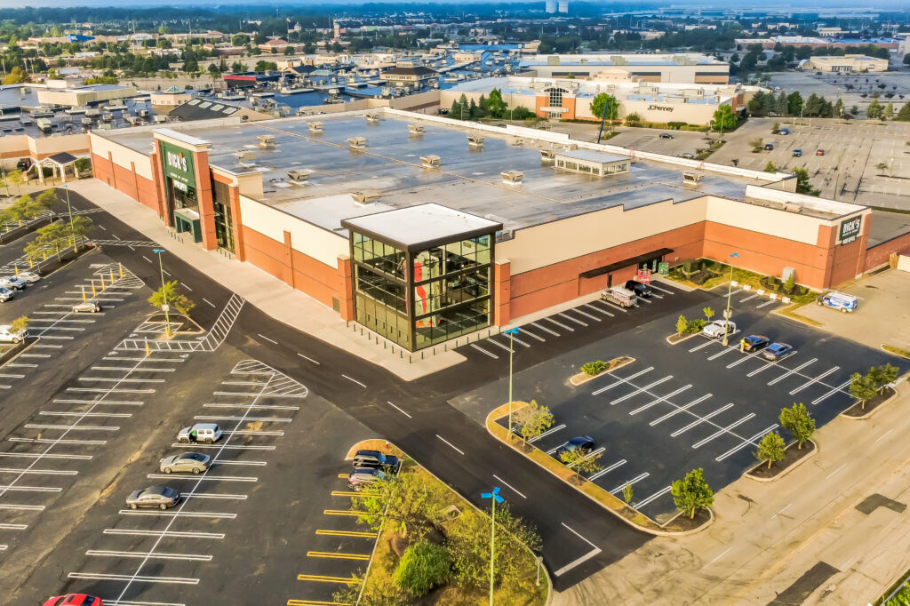Aerial view of a Dick’s Sporting Goods store in a large shopping center parking lot.