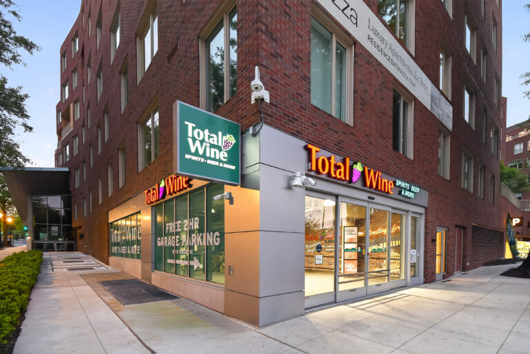 Total Wine & More storefront located on the corner of a brick apartment building, with signage indicating two-hour garage parking.