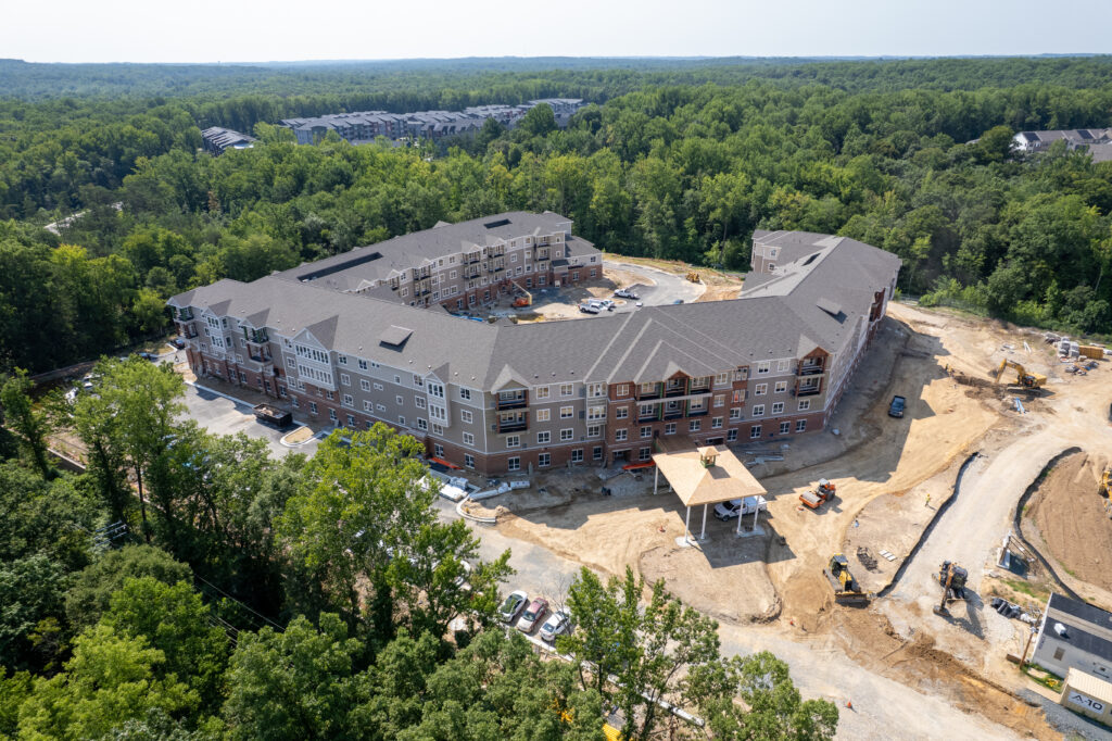 Aerial view of a multi-story apartment complex under construction, surrounded by forest.