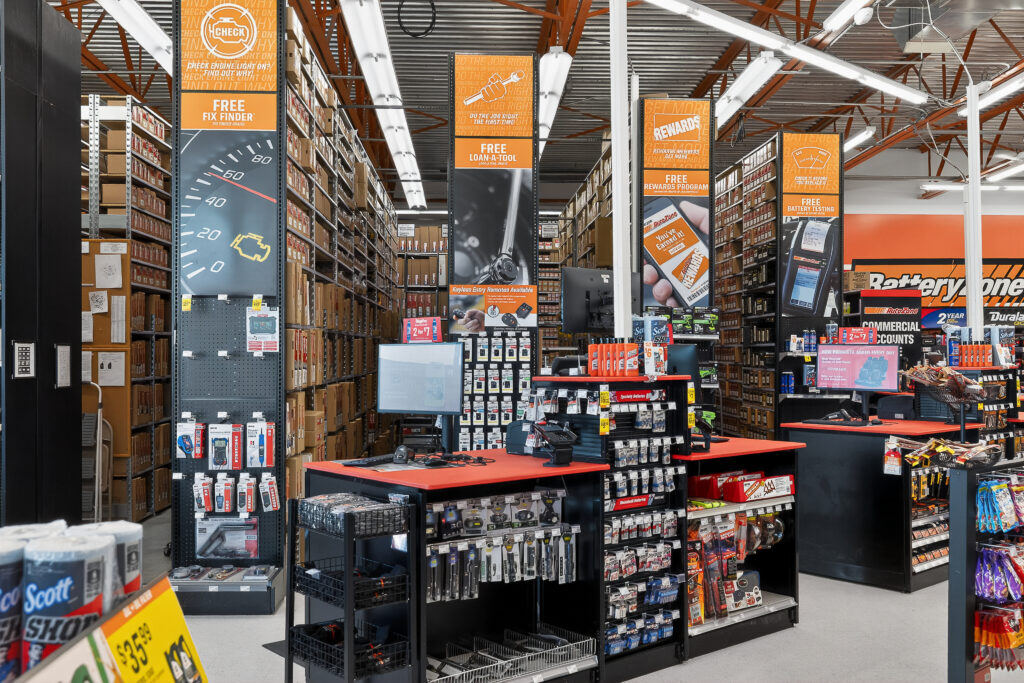 Interior of an auto parts store with aisles of inventory and signage advertising free services like check engine light testing and battery testing.