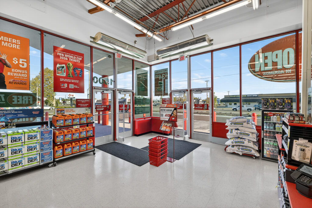 Interior of a retail store entrance with glass walls, merchandise displays, stacks of bags, and promotional posters for 2026 FIFA World Cup tickets and hiring.