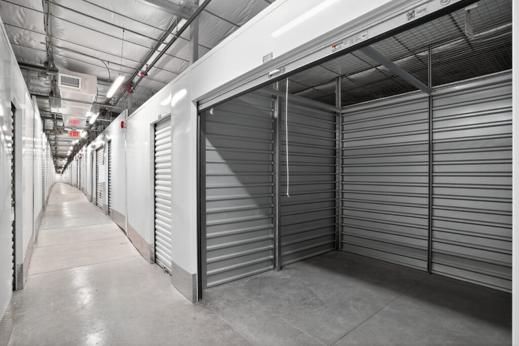 A hallway of indoor storage units, one with an open rolling metal door.