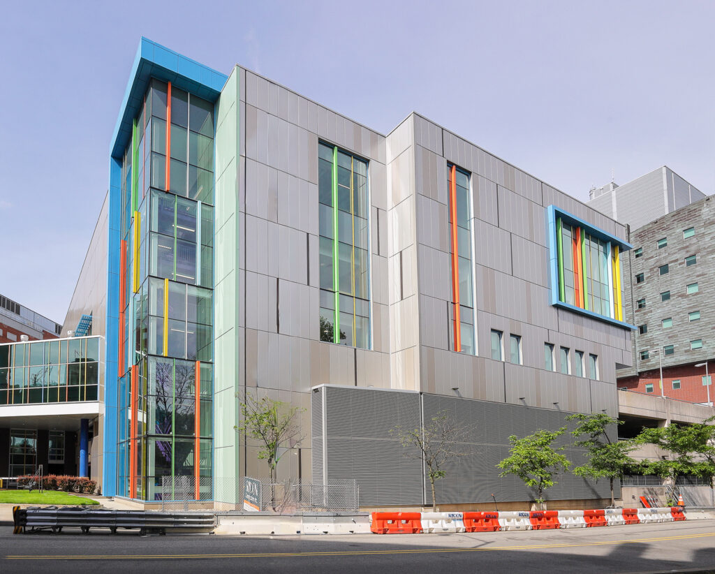 Modern multi-story building featuring a silver facade, glass windows, and colorful vertical accent panels.