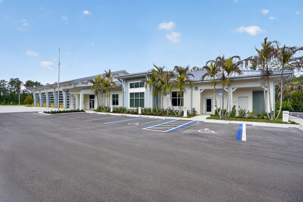 Modern, single-story commercial building with multiple garage bays and an asphalt parking lot featuring accessible parking spaces.