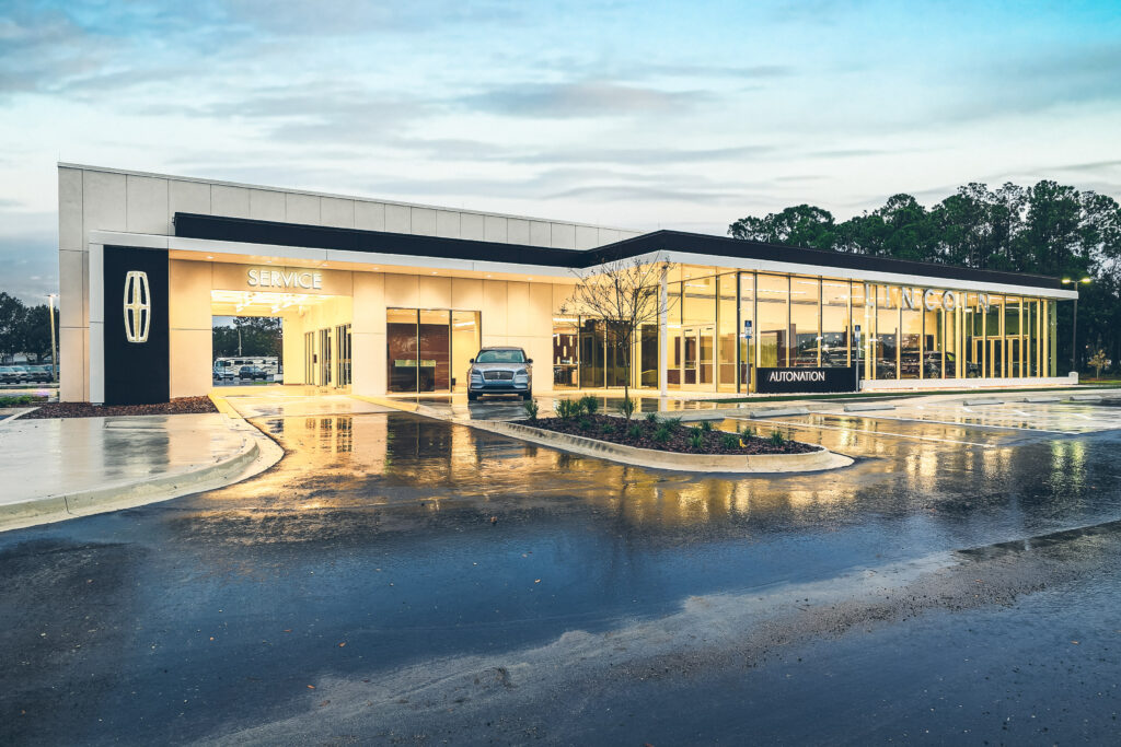 AutoNation Lincoln dealership building at dusk with a service bay and a vehicle parked in front.