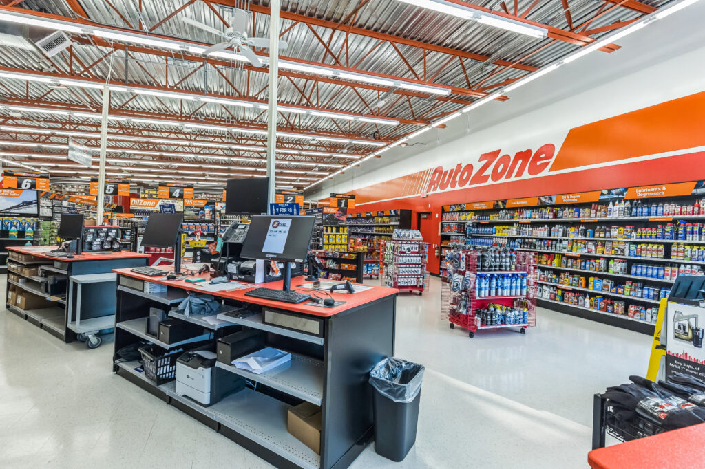 Interior of an AutoZone auto parts store with a service counter in the foreground and shelves of merchandise along the walls.