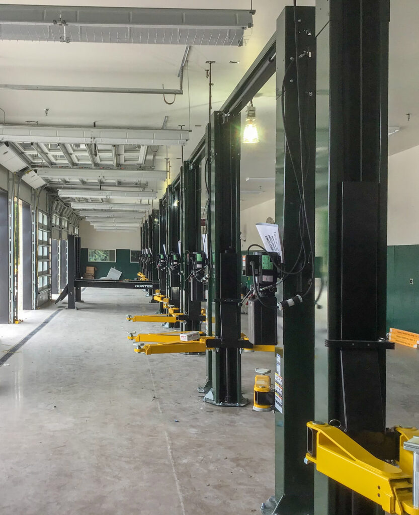A row of empty vehicle lifts inside an automotive repair shop.