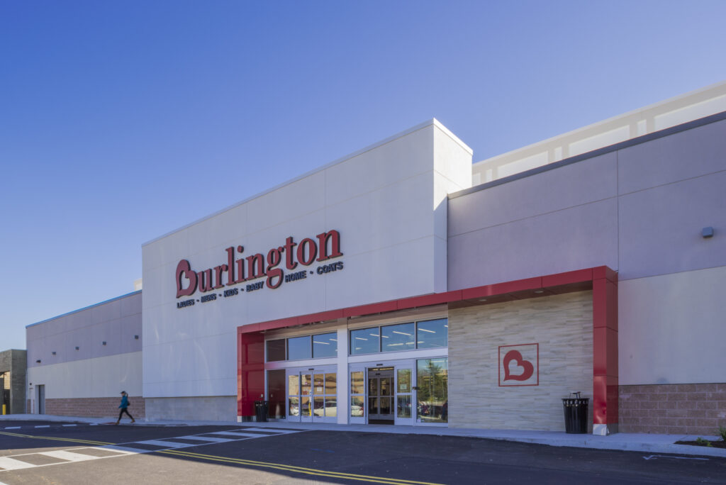 Exterior of a Burlington store with red signage and a pedestrian walking near the entrance.