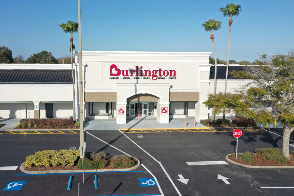 An aerial view of a Burlington store entrance in a shopping plaza with a parking lot in the foreground.