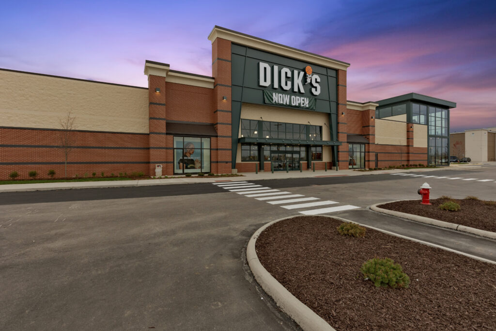 A Dick’s Sporting Goods store exterior with a “Now Open” banner hanging below the sign.