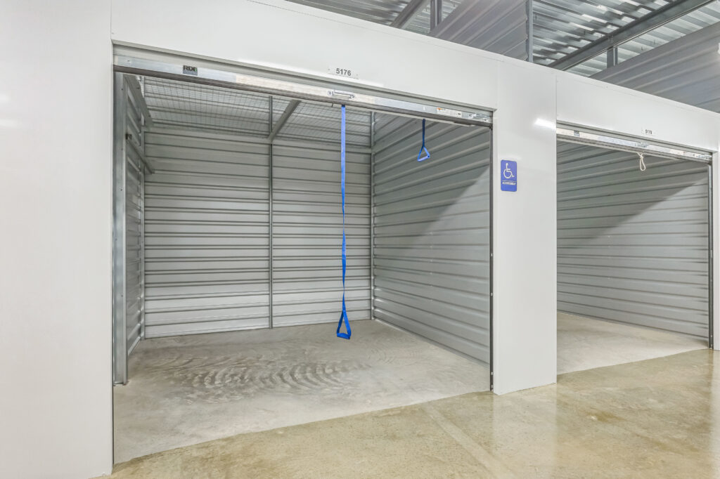 Empty self-storage unit with a blue accessibility sign and a pull-down strap attached to the door.