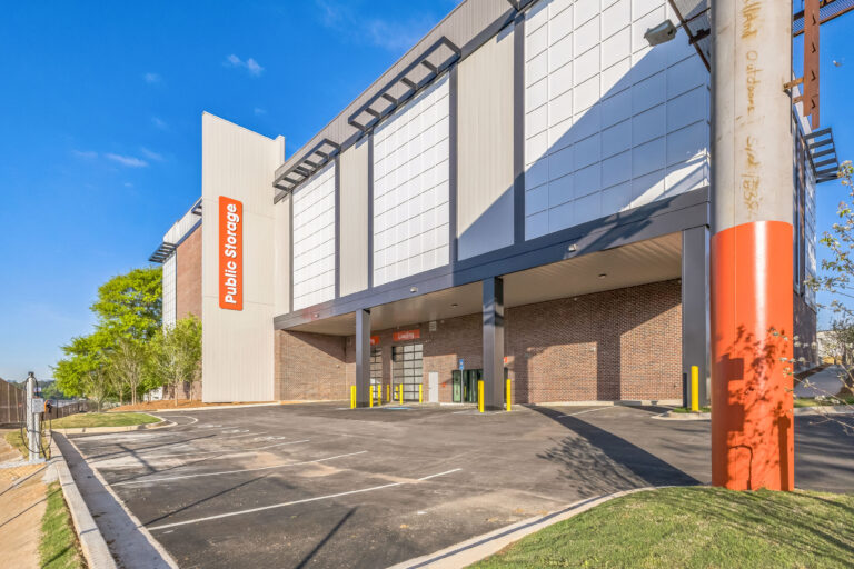 Exterior of a multi-story Public Storage facility with a paved parking lot and loading dock area.