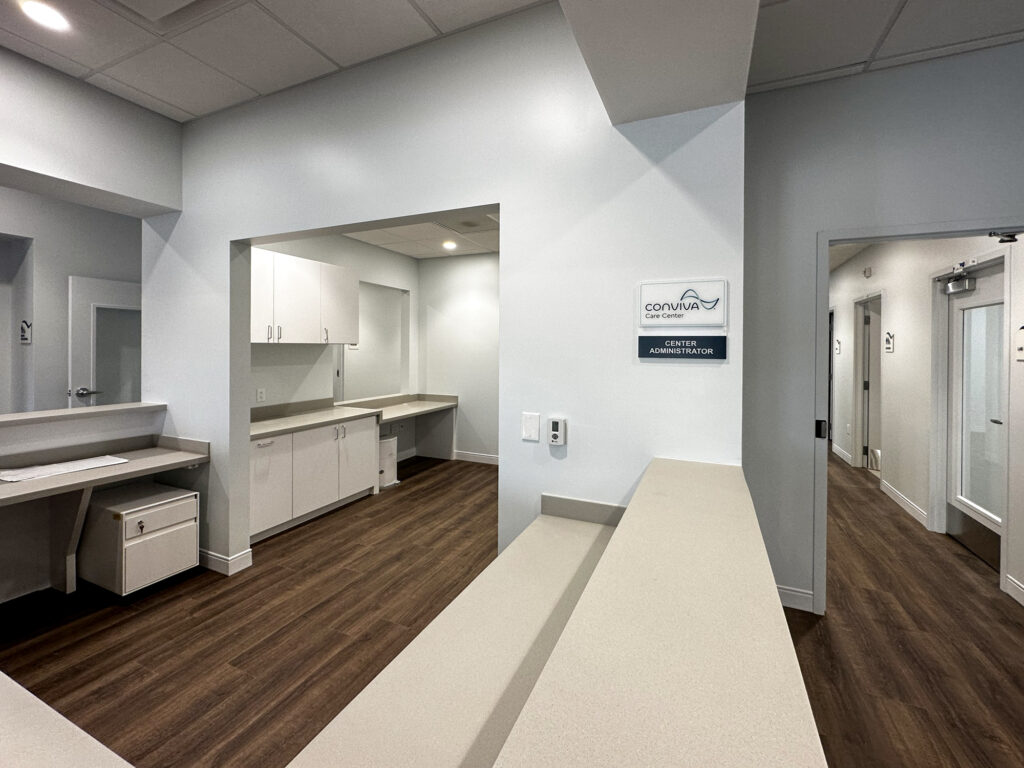 A reception area with a long counter and a sign for Conviva Care Center, Center Administrator.