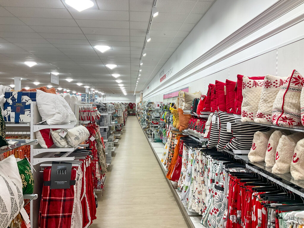 A store aisle featuring holiday-themed home decor, including patterned pillows, throws, and seasonal linens on display.
