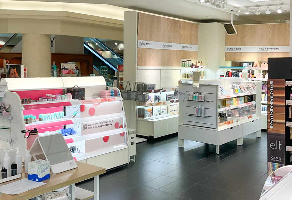 Interior view of a cosmetics and hair care retail section with product displays labeled by category, including styling tools and salon favorites.