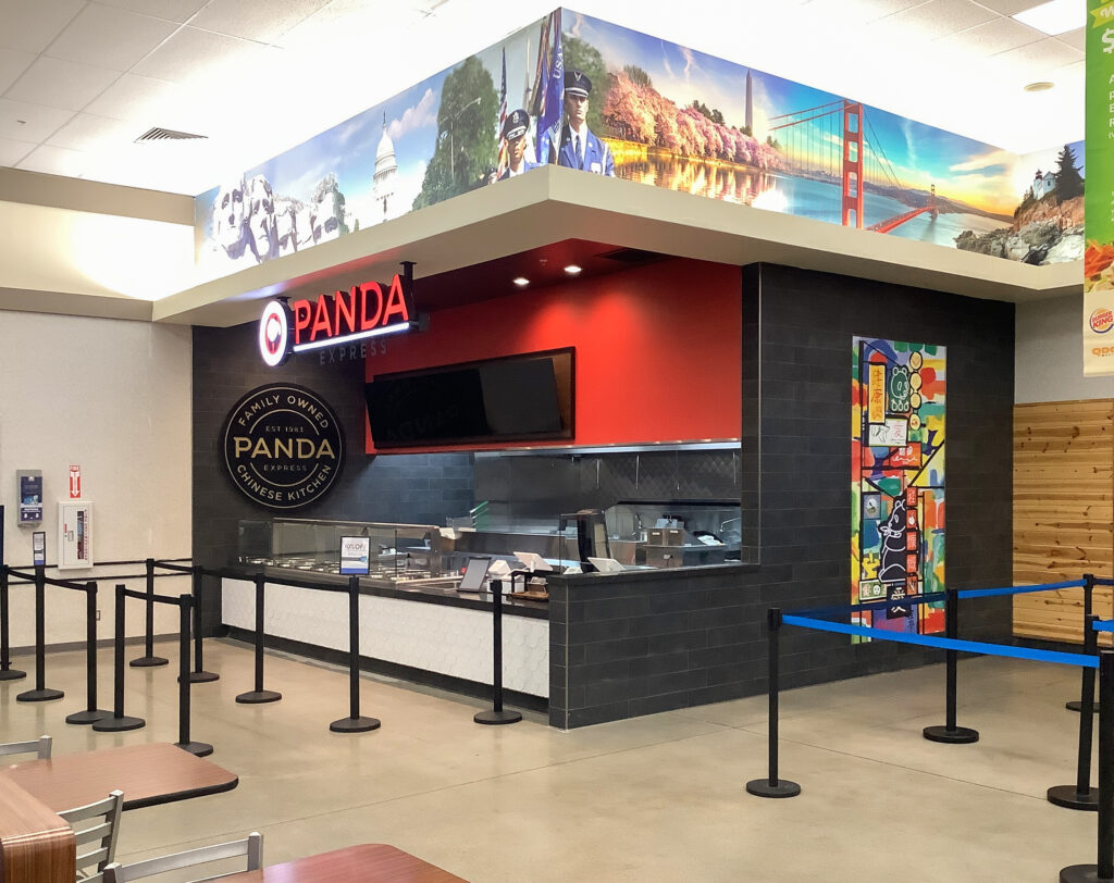 Panda Express restaurant storefront with a service counter and a mural of US landmarks on the upper wall.